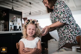 In Aberdeen, Hong Kong, the adorable flower girl makes a funny face while her aunt styles her hair before the wedding, adding a touch of playful charm to the moment.